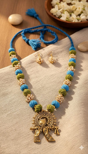 Necklace with blue and green beads and a gold pendant on a beige surface.