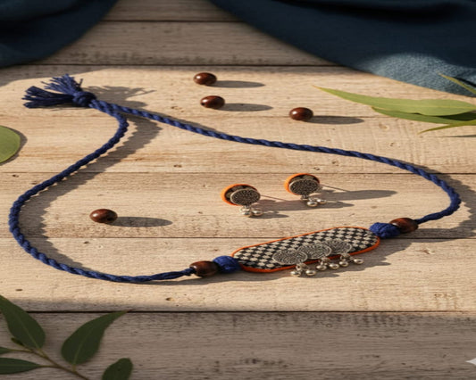 Jewelry set with blue necklace, earrings, and decorative item on a wooden surface.