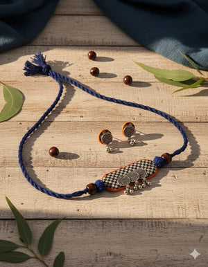 Jewelry set with blue necklace, earrings, and decorative item on a wooden surface.