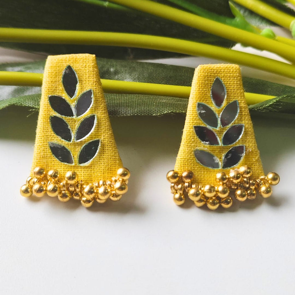 Yellow earrings with leaf designs and gold beads on a white background