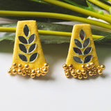 Yellow earrings with leaf designs and gold beads on a white background