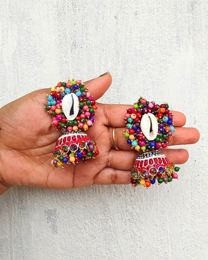 Colorful beaded earrings held in a hand against a light gray background