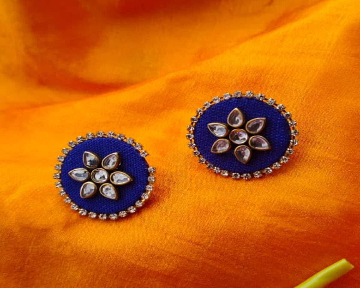 Blue floral earrings on an orange fabric background