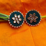 Pair of green earrings with floral designs on an orange fabric background