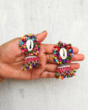 Colorful beaded earrings held in a hand against a light gray background